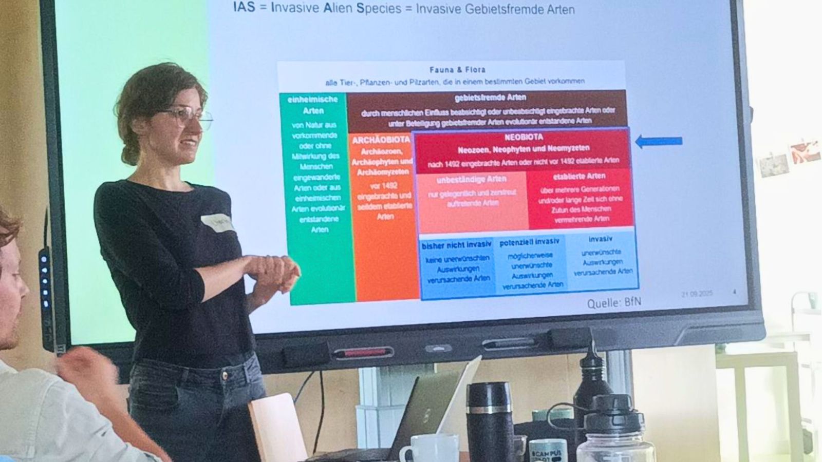 Die Referentin steht vor der Präsentation über invasive Arten