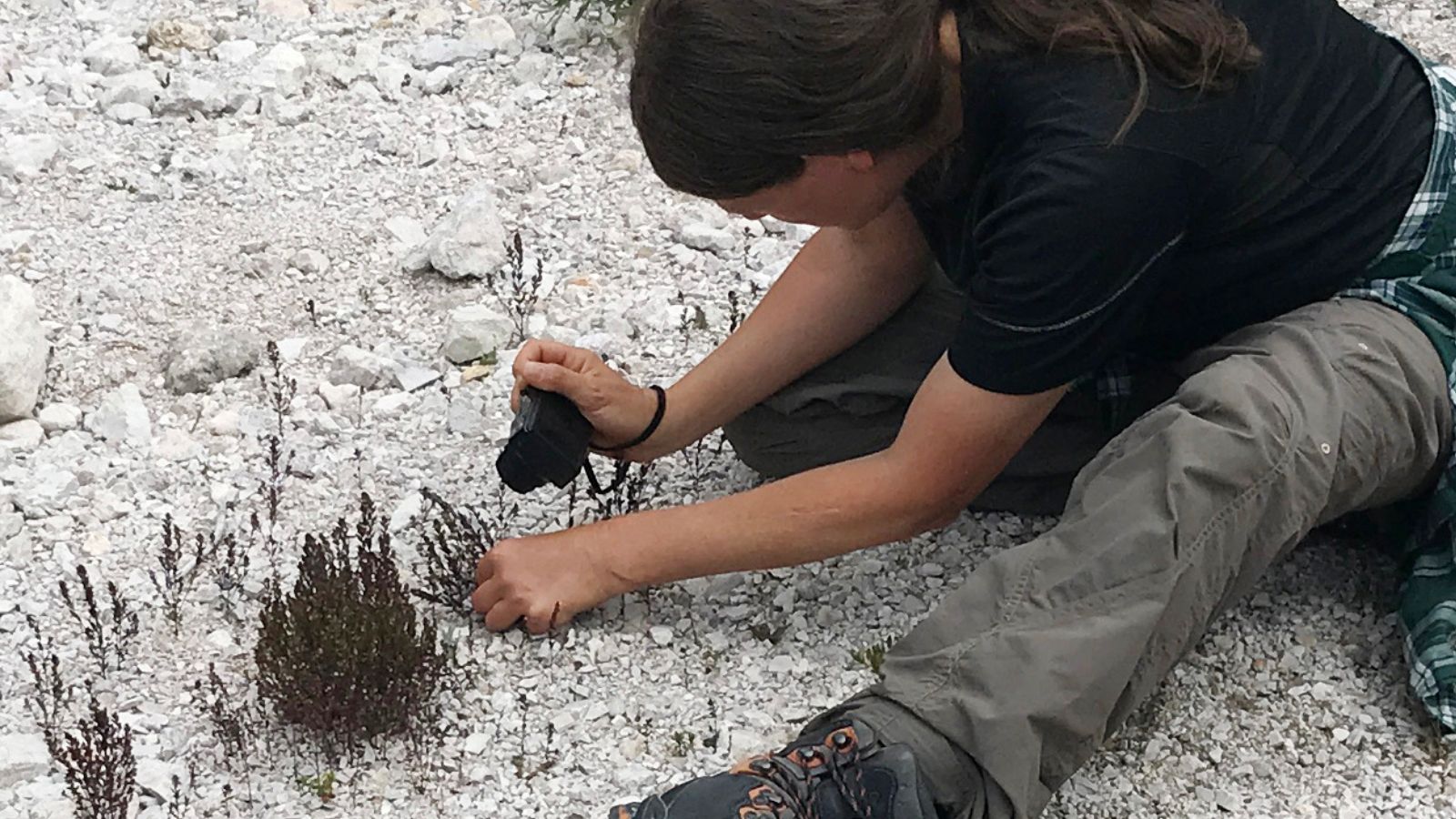 Irene Pardo sitzt auf dem Boden und fotografiert eine Pflanze